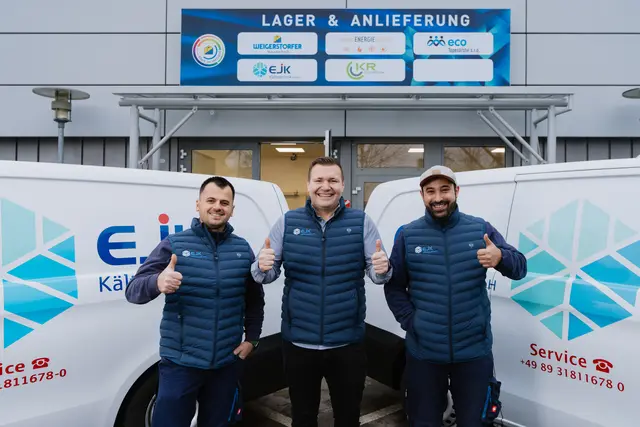 Team mit Daumen hoch vor den Fahrzeugen